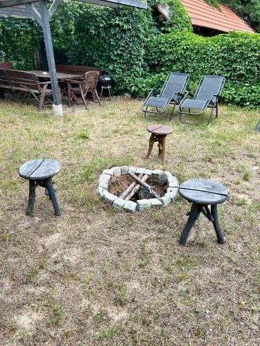 two picnic tables and benches next to a fire pit at Domek na wzgórzu in Tumiany