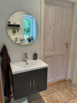 a bathroom with a sink and a mirror at Højmosegård værelse 1 in Varde