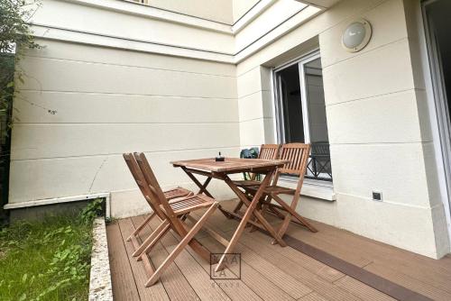 2 chaises et une table en bois sur une terrasse couverte dans l'établissement KAALA STAYS - APT spacieux Paris-Disneyland, à Noisy-le-Grand
