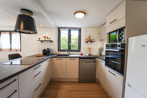 une cuisine avec des armoires blanches et des appareils noirs dans l'établissement Le crêt du lac charmant appartement au calme, à Sévrier