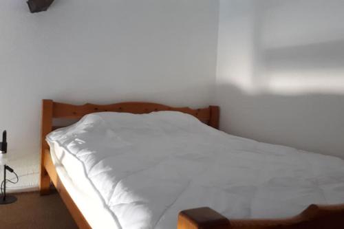 - une chambre avec un lit blanc et un cadre en bois dans l'établissement Magnifique petite maisonnette climatisée avec parking privatif, au Barcarès