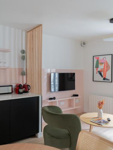un salon avec une télévision, une table et des chaises dans l'établissement Beauquartier - Butte aux Cailles II, à Paris