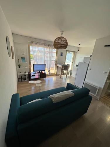 un salon avec un canapé bleu et une télévision dans l'établissement Studio lumineux, terrasse, piscine proche plages, à Fréjus