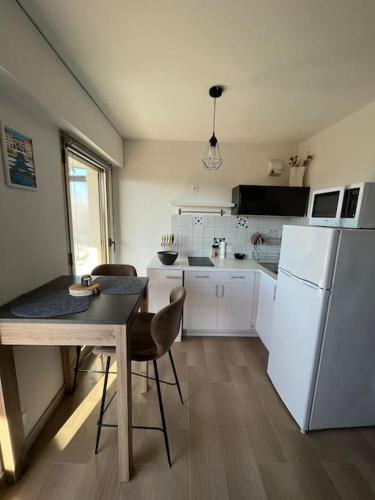 une cuisine avec une table et un réfrigérateur blanc dans l'établissement Studio lumineux, terrasse, piscine proche plages, à Fréjus