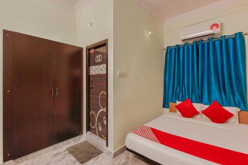 a bedroom with two beds with blue curtains and red pillows at Goldhorn Hotels & Banquet Mehdipatnam Near St Ann's college in Hyderabad
