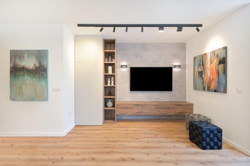Una sala de estar con un televisor de pantalla plana en una pared. en Elegance 3 BR in Gordon Beach by HolyGuest, en Tel Aviv