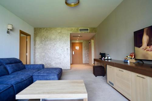 a living room with a blue couch and a flat screen tv at Belchin Garden SPA&Wellness in Belchin
