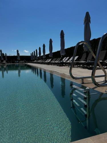 a pool of water with chairs and umbrellas at Belchin Garden SPA&Wellness in Belchin