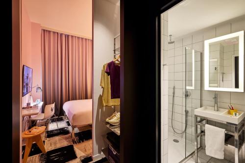a bathroom with a shower and a sink and a bedroom at Mama Shelter Bordeaux Centre in Bordeaux
