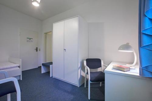 a room with a desk and a chair and a cabinet at Gästehaus im LWH in Lingen