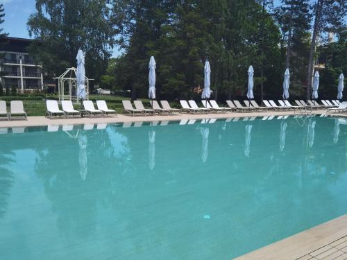 a large swimming pool with lounge chairs and umbrellas at Belchin Garden SPA&Wellness in Belchin