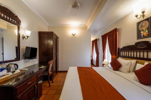 a hotel room with a large bed and a television at Hotel Arches in Cochin