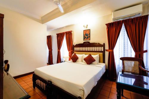 a bedroom with a large bed with red curtains at Hotel Arches in Cochin