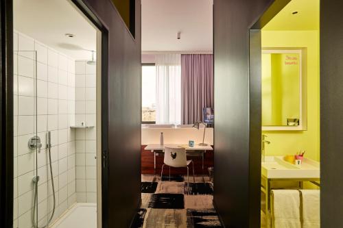 a bathroom with a shower and a sink and a table at Mama Shelter Bordeaux Centre in Bordeaux