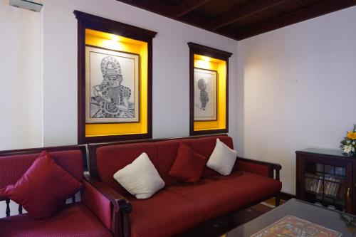 a living room with a red couch and two pictures at Hotel Arches in Cochin