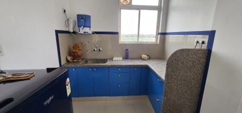 una pequeña cocina con armarios azules y fregadero en Lotus Diamerisma - 2BHK Furnished Apartment in Jodhpur - Peaceful Retreat Away from City Traffic, en Jodhpur