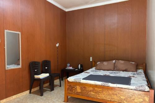 a bedroom with a bed and two chairs and a mirror at Family 24 Hotel near Pantai Cipatujah in Cipatujah