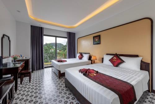 a hotel room with two beds and a desk at Le Maison Tam Coc Boutique Hotel in Ninh Binh