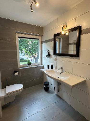 a bathroom with a sink and a toilet and a mirror at MEINpartments - Modern Business Apartment in Wolfsburg