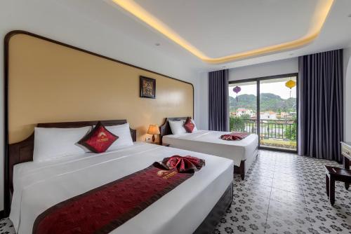 a hotel room with two beds and a balcony at Le Maison Tam Coc Boutique Hotel in Ninh Binh