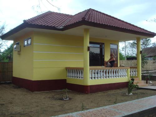 a small yellow house with a woman sitting in the window at Kalinka Inn in Gili Meno
