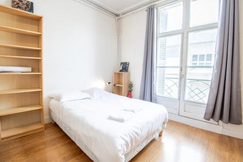 une chambre avec un lit blanc et une grande fenêtre dans l'établissement Le Petit Emile Zola, à Tours