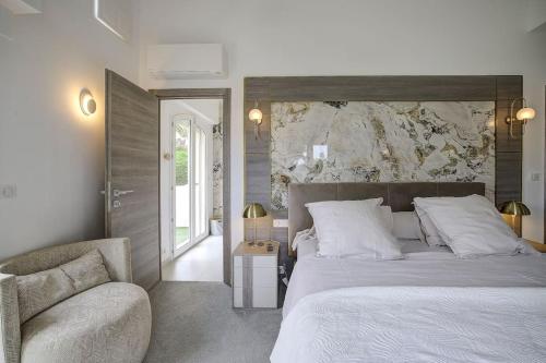 a bedroom with a large bed and a chair at Twin Luxurious Villas 8 BR Pool in Vallauris in Vallauris