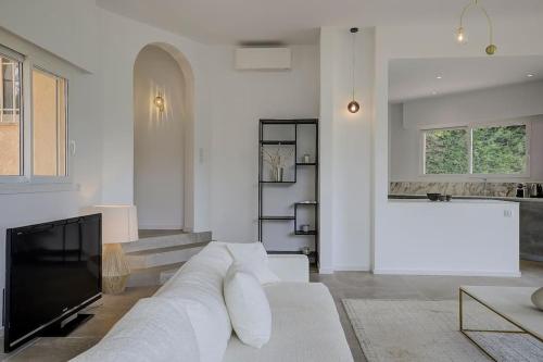a living room with a white couch and a tv at Twin Luxurious Villas 8 BR Pool in Vallauris in Vallauris