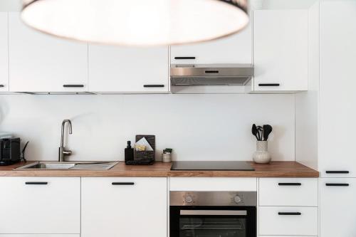 a kitchen with white cabinets and a sink at Lario Suite Apartments by Quokka 360 - With parking Next to Como City in Como