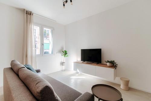 a white living room with a couch and a tv at Lario Suite Apartments by Quokka 360 - With parking Next to Como City in Como
