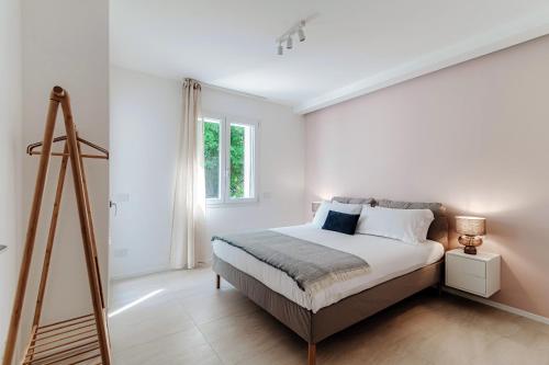 a white bedroom with a bed and a window at Lario Suite Apartments by Quokka 360 - With parking Next to Como City in Como