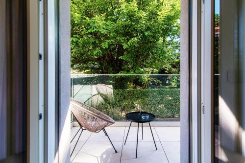 an open door to a patio with two chairs on a balcony at Lario Suite Apartments by Quokka 360 - With parking Next to Como City in Como