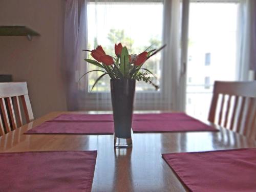a vase with red flowers sitting on a table at Apartmani Davorka in Krk
