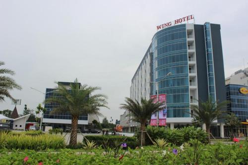 a hotel building with palm trees in the foreground at Wing Hotel Kualanamu Airport in Medan