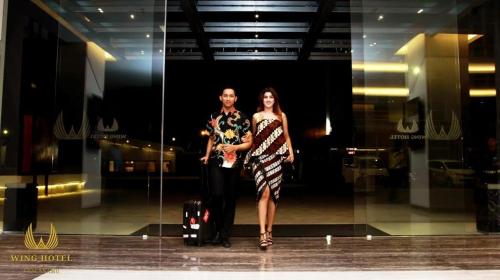 a man and a woman standing in front of a window at Wing Hotel Kualanamu Airport in Medan