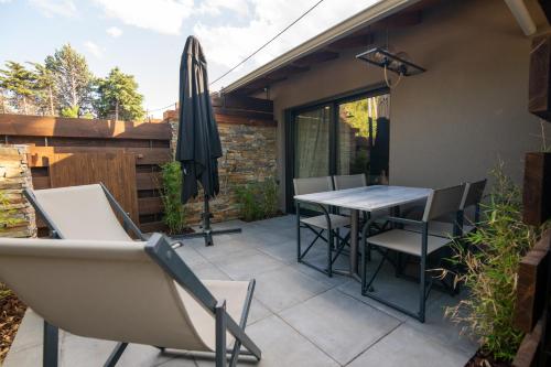 a patio with a table and chairs and an umbrella at Sylvia Camping & Luxury Suites, Panel Hospitality Homes & Villas in Litochoro