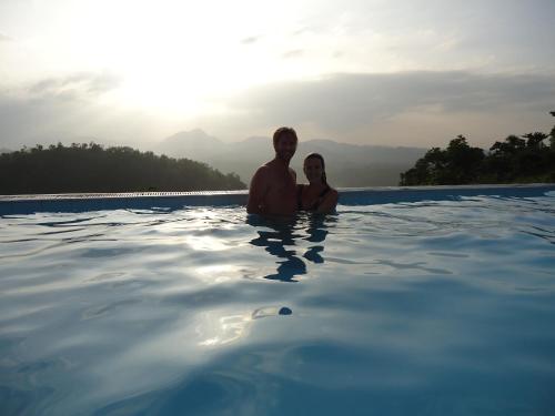 un hombre y una mujer sentados en una piscina en Sky Lodge en Kandy