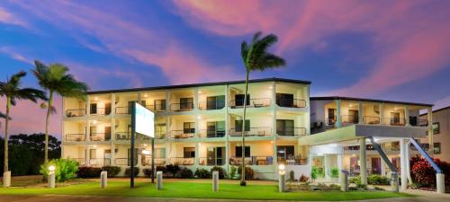 a building with palm trees in front of it at L'Amor Holiday Apartments in Yeppoon
