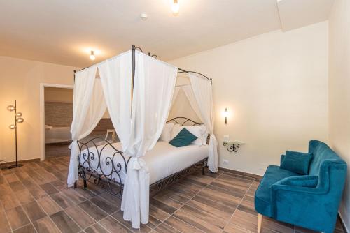 a bedroom with a canopy bed and a blue chair at La Ninfa Hotel in Bagni di Lucca