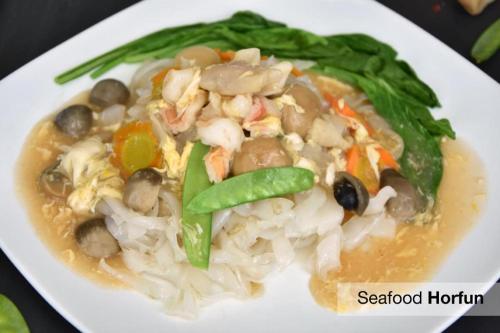 a white plate of soup with vegetables and mushrooms at Mega Permata Hotel in Padangsidimpuan