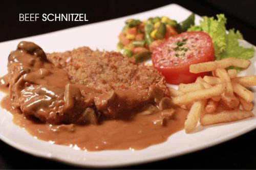 a plate of food with meat and french fries and a salad at Mega Permata Hotel in Padangsidimpuan