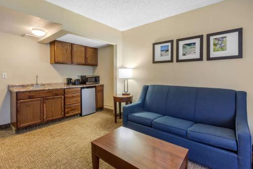 a living room with a blue couch and a kitchen at Comfort Inn St Petersburg North in St. Petersburg