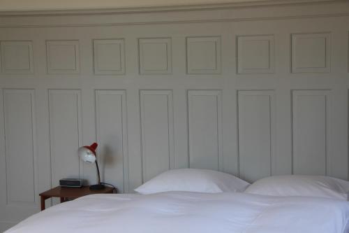 a bed with white sheets and a lamp on a table at Militärkantine St. Gallen in St. Gallen