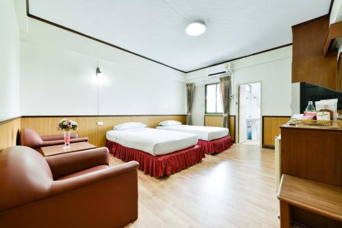 a hotel room with two beds and a couch at Nice Palace Hotel in Bangkok