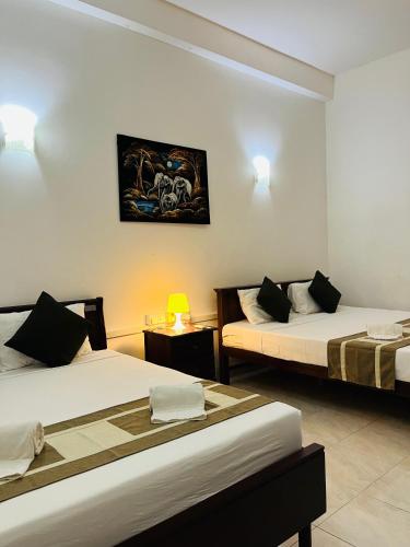 a hotel room with two beds and a table at Hotel Blue Bird in Negombo