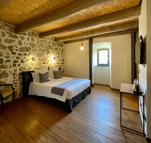a bedroom with a bed and a stone wall at Domaine de la Planche de Melussac in Cussac-sur-Loire