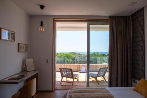 a bedroom with a door open to a patio with chairs at Villa AzaiTu Suites in Porto-Vecchio