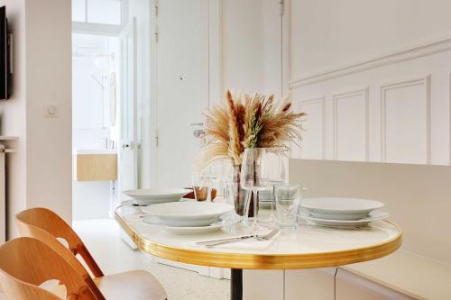 une salle à manger avec une table, des assiettes et des verres dans l'établissement Cosy apartment - 1BR-4P - Jardin du Luxembourg, à Paris