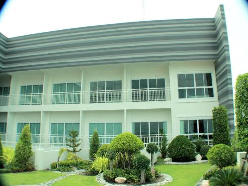 a large white building with trees and bushes at The Grace Residence in Surin