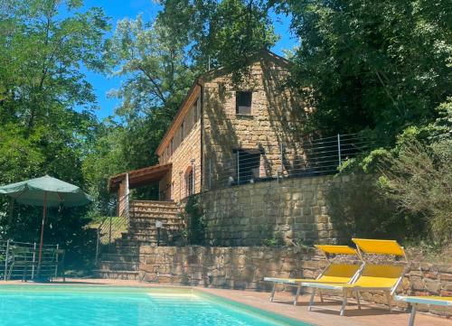 a resort with a pool and two chairs and a building at Villa Massignano in Gualdo di Macerata